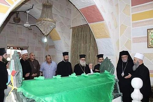 500px-Druze_and_Christians_in_Syria Prawosławni duchowni chrześcijańscy i przywódcy druzyjscy stoją wokół grobowca nakrytego zielonym suknem we wnętrzu sanktuarium w Syrii
