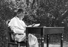 Św. Pius X, czyli dobroć przemieniona w lwa, który zachowuje łagodność Archiwalne czarno-białe zdjęcie: św. Pius X w białej sutannie i kapeluszu saturno czyta dokumenty przy drewnianym stoliku w ogrodzie.