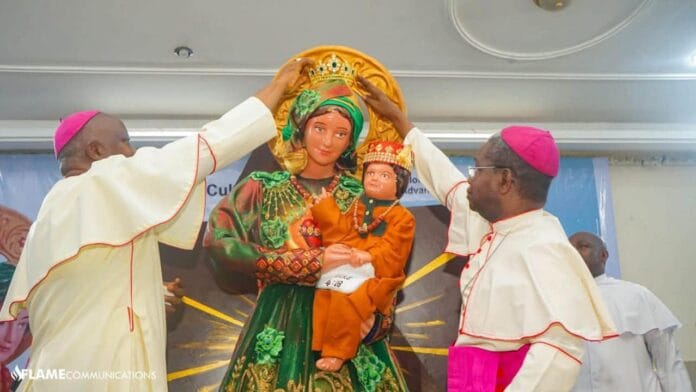 Our-Lady-Queen-of-Nigeria-Regina-Nigeriae-1 Dwaj nigeryjscy biskupi koronują figurę Matki Bożej z Dzieciątkiem Jezus, ubraną w zieloną i złotą szatę oraz korale — zdjęcie ilustracyjne.