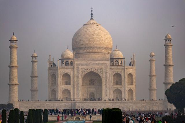 Taj-Mahal-Agra-Uttar-Pradesh-India Tadż Mahal z białego marmuru z centralną kopułą i czterema minaretami, tłumy zwiedzających u podnóża mauzoleum, Agra w Indiach.