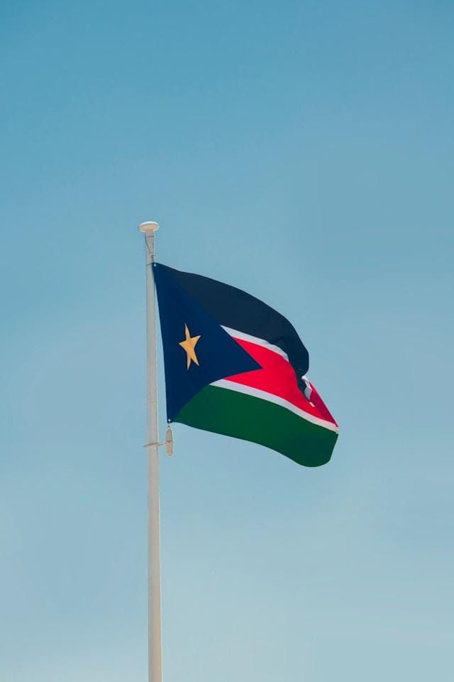 aboodi-vesakaran-gzNz8Xjd5Kk-unsplash Flaga narodowa Sudanu Południowego powiewająca na maszcie na tle błękitnego nieba