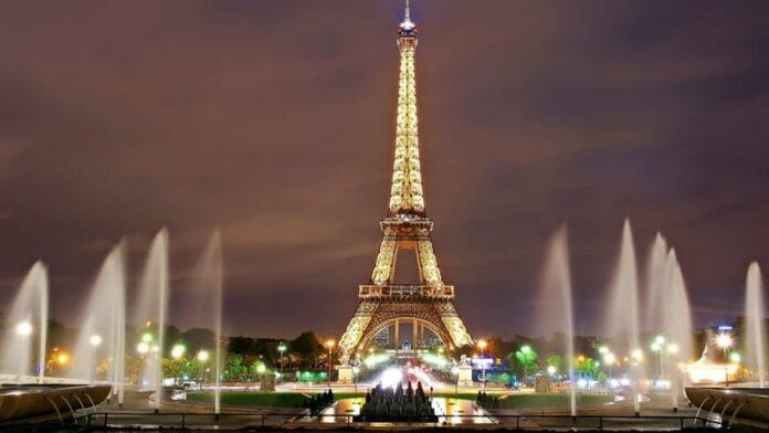 architecture-sunset-night-city-eiffel-tower-paris-1046619-pxhere.com_ Podświetlona wieża Eiffla nocą, z fontannami ogrodów Trocadéro na pierwszym planie — zdjęcie ilustracyjne Paryża