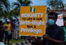 Przemoc wobec katolików w Nigerii: ksiądz zabity w domniemanej zasadzce Mężczyzna w maseczce podczas protestu w Nigerii trzyma tablicę z hasłem w obronie prawa do życia oraz nigeryjską flagą
