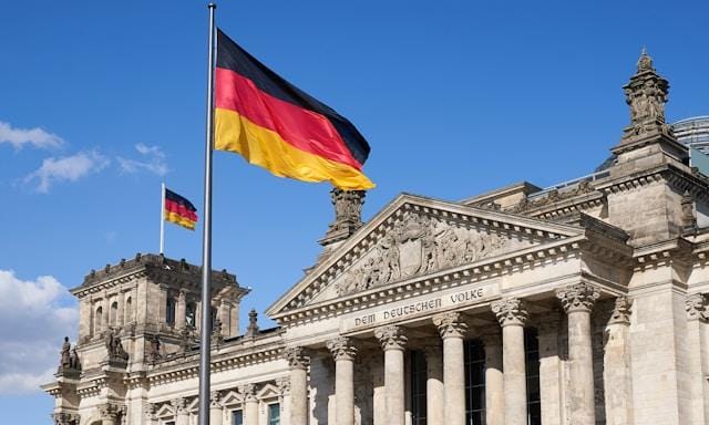 norbert-braun-oMpz5DU19DU-unsplash-1 Flaga Niemiec powiewa przed budynkiem Reichstagu w Berlinie z inskrypcją „Dem Deutschen Volke”
