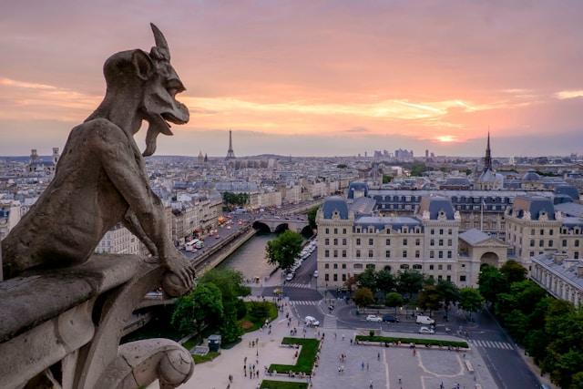 pedro-lastra-suRvdiwP9Pk-unsplash Rzeźba gargulca spoglądająca na panoramę Paryża w pobliżu Notre-Dame o zachodzie słońca