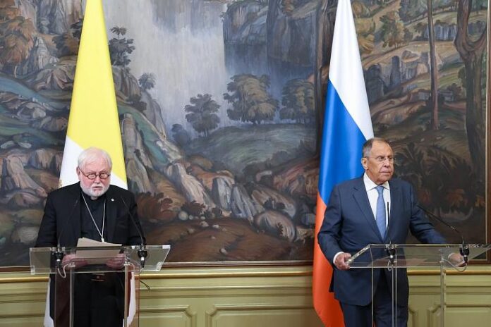 unnamed-file Abp Paul Richard Gallagher i Siergiej Ławrow przy mównicach na konferencji prasowej w Moskwie, w tle flagi Watykanu i Rosji.