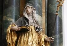 Święta Hildegarda z Bingen: poprzez jej wizje Bóg przemawiał do papieży i cesarzy Złocona drewniana rzeźba św. Hildegardy z Bingen w habicie benedyktyńskim, trzymającej otwartą księgę i pastorał ksieni na tle marmurowych kolumn.