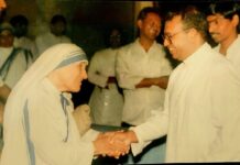 Matka Teresa na ekranie: premiera filmu „Mother Teresa – Prophet of Compassion” w Kalkucie Matka Teresa z Kalkuty w białym sari z niebieskimi prążkami ściska dłoń uśmiechniętego księdza w okularach; w tle mężczyźni w białych koszulach