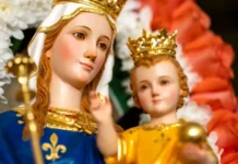 Dar czystości: nauka św. Jana z Ávili o łasce Bożej i wstawiennictwie Maryi Ukoronowana figura Matki Bożej w niebieskim płaszczu w lilie, trzymająca ukoronowane Dzieciątko Jezus, otoczona białymi i czerwonymi kwiatami.