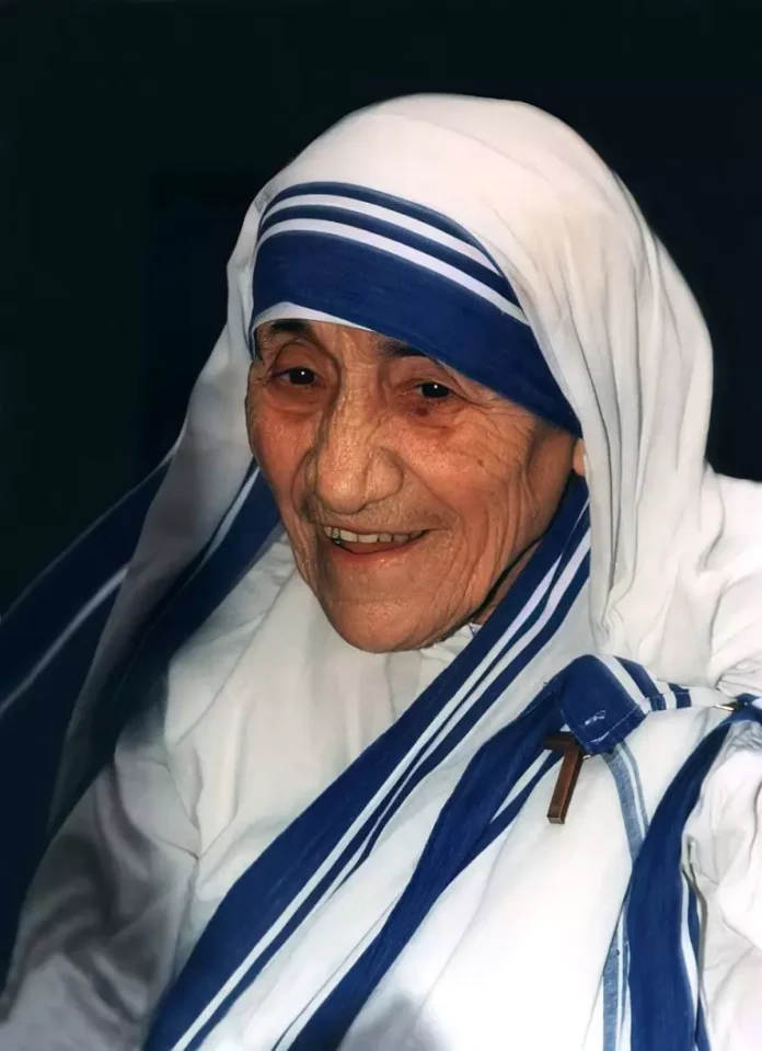 960px-Mother_Teresa_1-768x1058-1 Matka Teresa z Kalkuty — uśmiechnięta starsza zakonnica w białym sari z niebieskimi paskami i drewnianym krzyżykiem; portret archiwalny z 1995 roku.