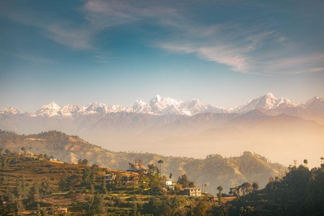 Himalayas-seen-from-Nepal Ośnieżone szczyty Himalajów nad tarasowymi wzgórzami i domami w wiejskim Nepalu; zdjęcie ilustracyjne, nie przedstawia terenów dotkniętych powodzią
