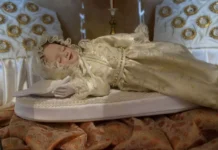 Narodzenie Maryi: przychodzi Stworzenie doskonałe, a zło zaczyna upadać Dewocyjna figura Maryi jako śpiącego niemowlęcia, w kremowej sukni ze złotym haftem i koronkowym czepku, ułożona na białej poduszce zdobionej perłami