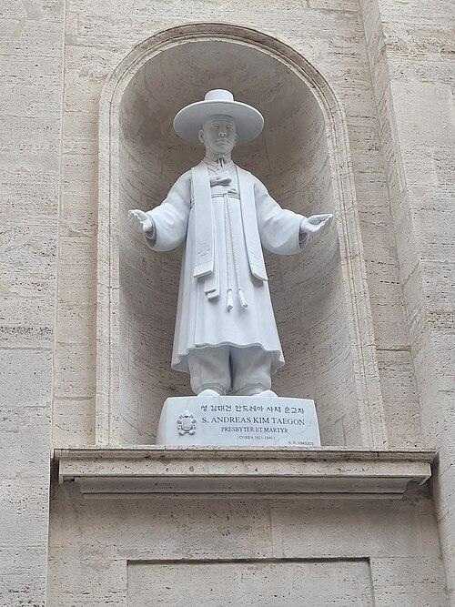 Kim_Taegon Biała marmurowa figura św. Andrzeja Kim Taegona w kapłańskim stroju, we wnęce fasady, z inskrypcją „S. Andreas Kim Taegon, Presbyter et Martyr”.