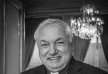 Papieska wizyta we Francji coraz bliżej. Kard. Aveline wzywa do duchowej gotowości Uśmiechnięty kard. Jean-Marc Aveline w koloratce i ciemnej marynarce, z krzyżem pektoralnym – czarno-biały portret we wnętrzu z żyrandolem.