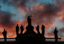 Kardynał Reina wzywa do wzmocnienia więzi między papieżem Leonem a diecezją rzymską Sylwetki posągów Chrystusa i świętych na szczycie bazyliki św. Jana na Lateranie o zachodzie słońca, na tle ognistego nieba