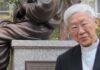 Hongkong: oddalona apelacja kard. Josepha Zena i powierników Funduszu 612 Kard. Joseph Zen w czarnym stroju duchownego z koloratką przy brązowym pomniku na granitowym cokole z chińską inskrypcją — zdjęcie archiwalne.