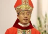 Nowy arcybiskup Chongqing wyświęcony w Chinach w ramach umowy ze Stolicą Apostolską Duchowny w czerwonym ornacie i mitrze biskupiej podczas liturgii, w tle białe kwiaty — zdjęcie ilustrujące święcenia biskupie w Chongqing.