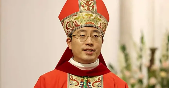 check-chinese-archdiocese-gets-new-bishop-under-sino-vatican-deal-6aa023f3101e5_600 Duchowny w czerwonym ornacie i mitrze biskupiej podczas liturgii, w tle białe kwiaty — zdjęcie ilustrujące święcenia biskupie w Chongqing.