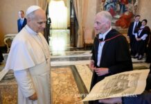 Leon XIV do Oriel College: szukajcie prawdy i brońcie godności człowieka Papież Leon XIV rozmawia z mężczyzną w todze akademickiej, trzymającym dużą rycinę budynku kolegium, podczas audiencji w sali Pałacu Apostolskiego.