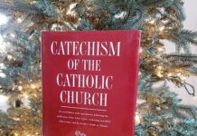 Kard. Schönborn broni Katechizmu jako fundamentu jedności Kościoła Czerwony tom „Catechism of the Catholic Church” (wydanie CCCB) na wiklinowym siedzisku na tle choinki z białymi lampkami