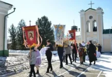 Widzieć oblicze Boga w czasie wojny: misja pokoju jezuity na Syberii Procesja wiernych, w tym dzieci, z chorągwiami z wizerunkami Chrystusa i Matki Bożej przed kościołem z białą dzwonnicą w słoneczny zimowy dzień