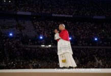 Leon XIV i nowe pokolenie Papież w białej sutannie i czerwonym mucecie ze złożonymi dłońmi na scenie, w tle wypełnione trybuny Stade de France